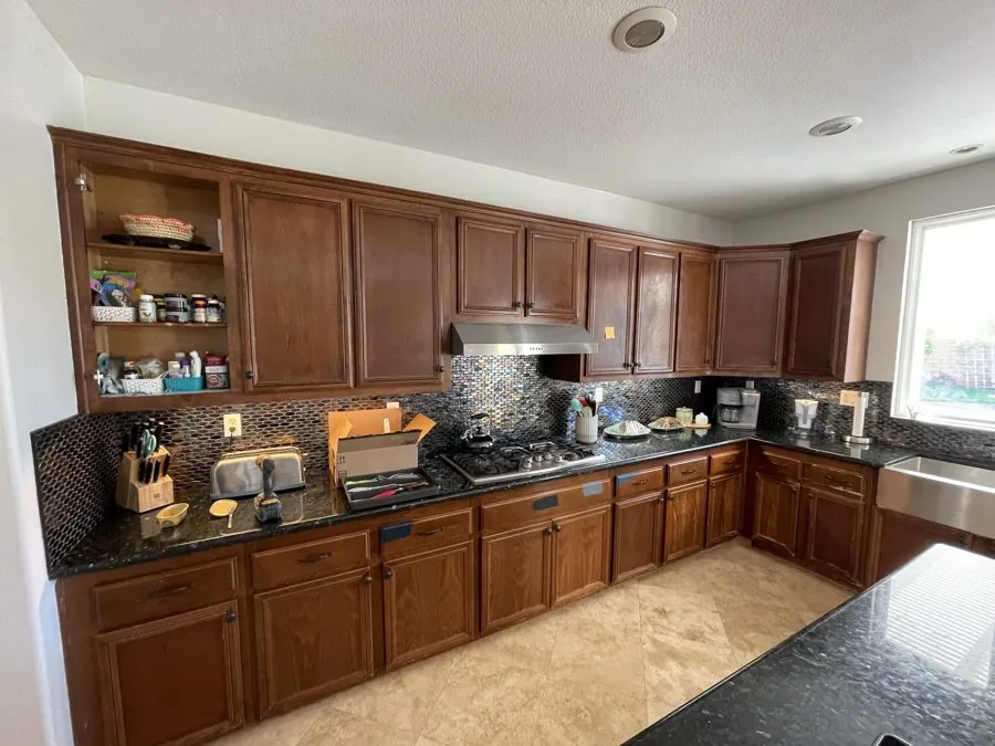 Kitchen with dated wood cabinets before repaint