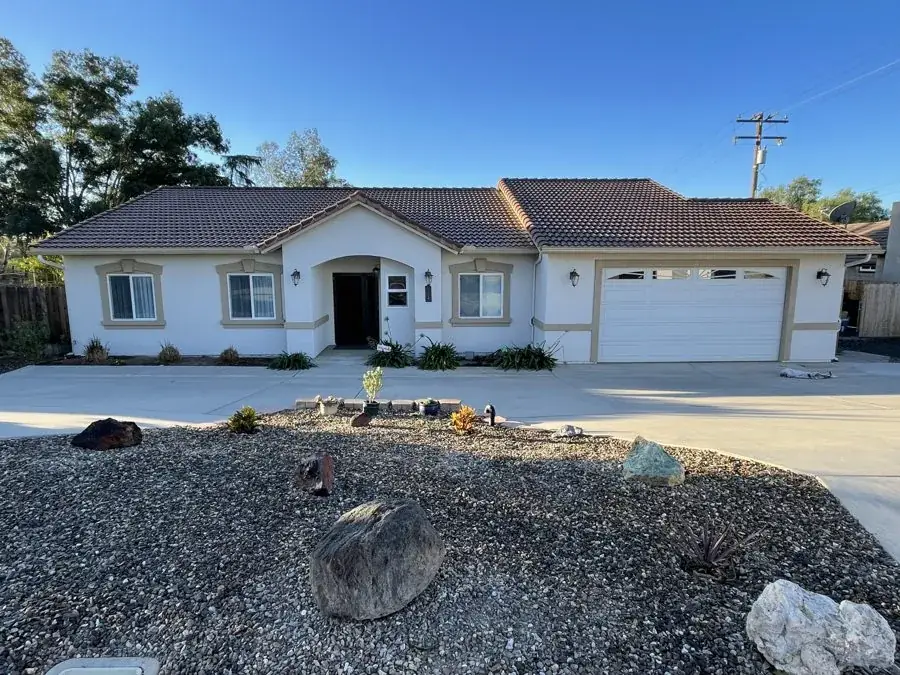Stucco home after exterior repaint in white with tan trim