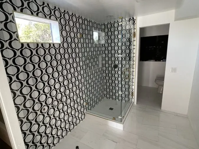 Bathroom Remodel — Floor-to-ceiling patterned wall tile with a frameless glass corner shower and marble-look floor tile.